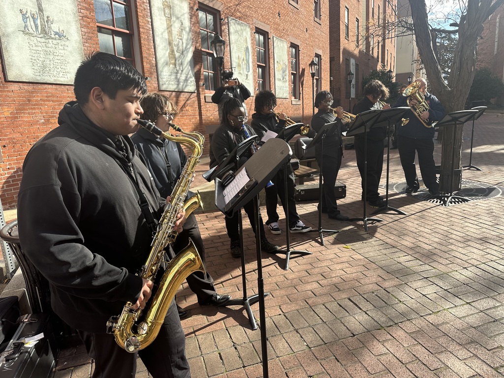 A group of William Penn Senior High School students are performing with brass and woodwind instruments outdoors. 