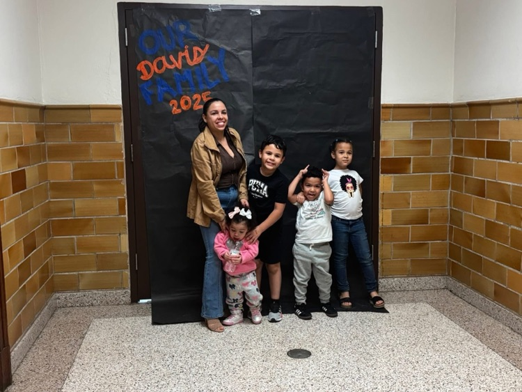 An adult and four children are standing in front of a black backdrop that says “ Our Davis Family 2025”