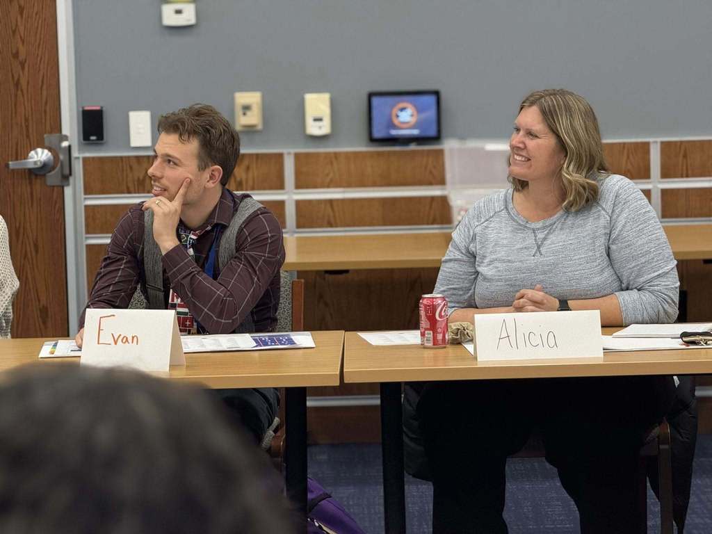 Two district staff members are sitting at a table with name tags in a conference room. 