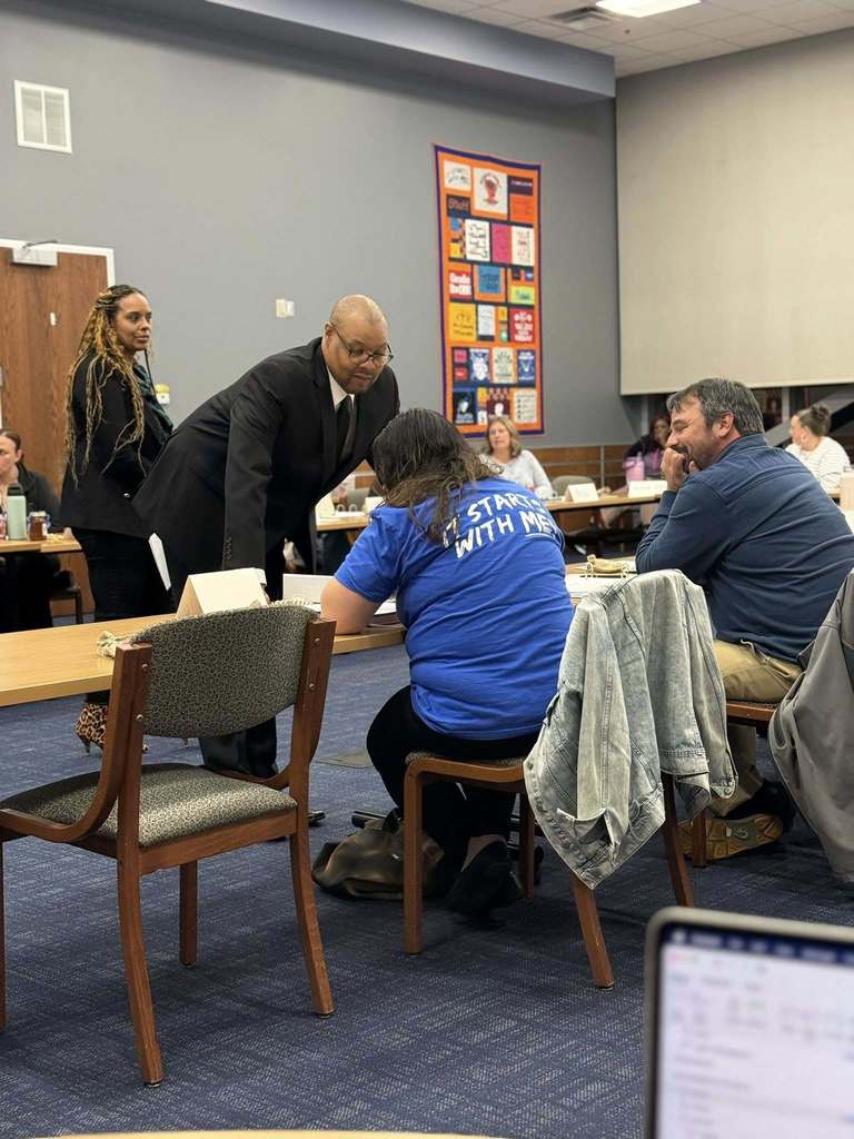 A conference room meeting with a group of district staff members, engaging in discussion. 