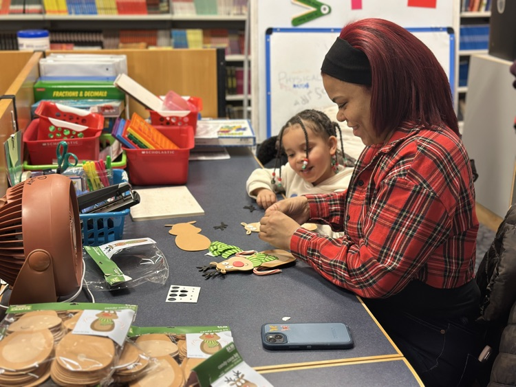 A woman and a young girl are doing arts and crafts in a school library.