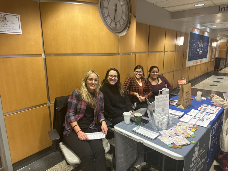 Four district staff members are sitting a table filled with supplies and resources.