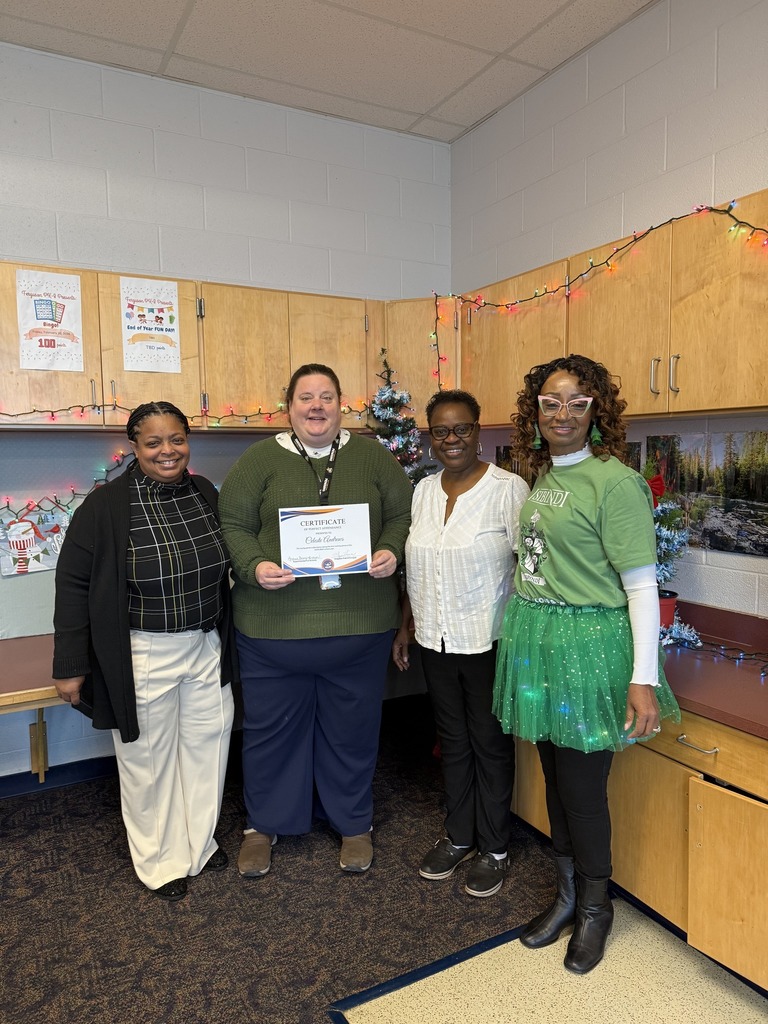 Superintendent of Schools, Dr. Berry-Brown, is standing with Ferguson PreK-8 Principal, Mrs. Lisa Love, a district staff member and a community member in a school classroom. The district staff member is holding a certificate.