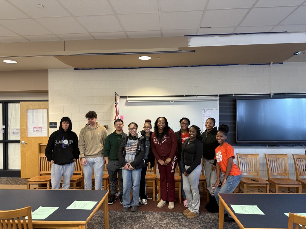 A group of William Penn Senior High School alumni students are standing together in front of a whiteboard in a school library.