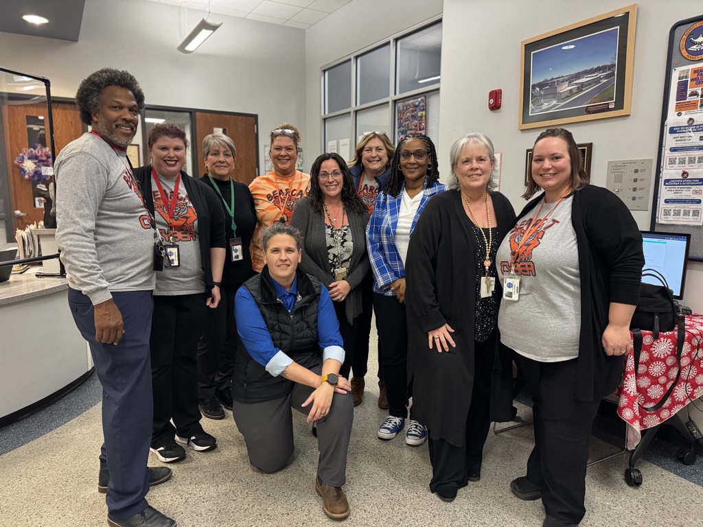 A group of nine district staff members are standing together in a lobby area.