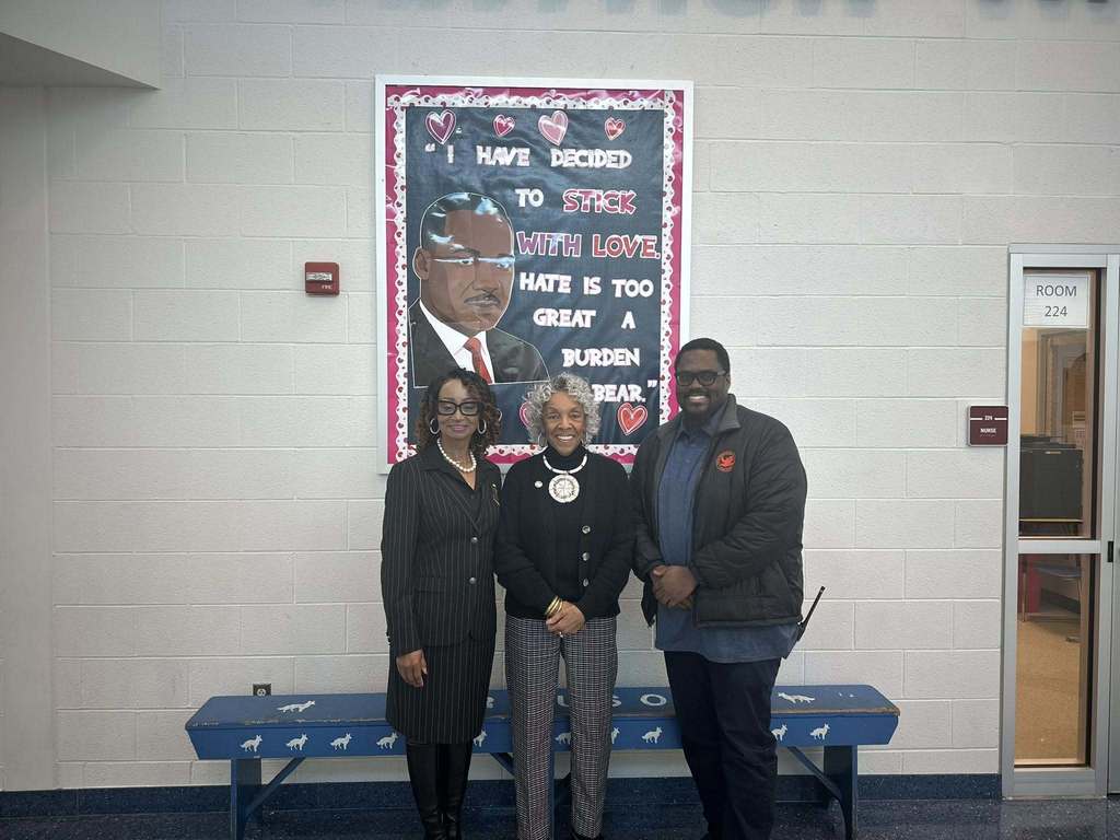 District administration and Representative Carol Hill-Evans are standing in a school hallway in front of a colorful mural of Martin Luther King Jr. with the quote, "I have decided to stick with love. Hate is too great a burden to bear." 