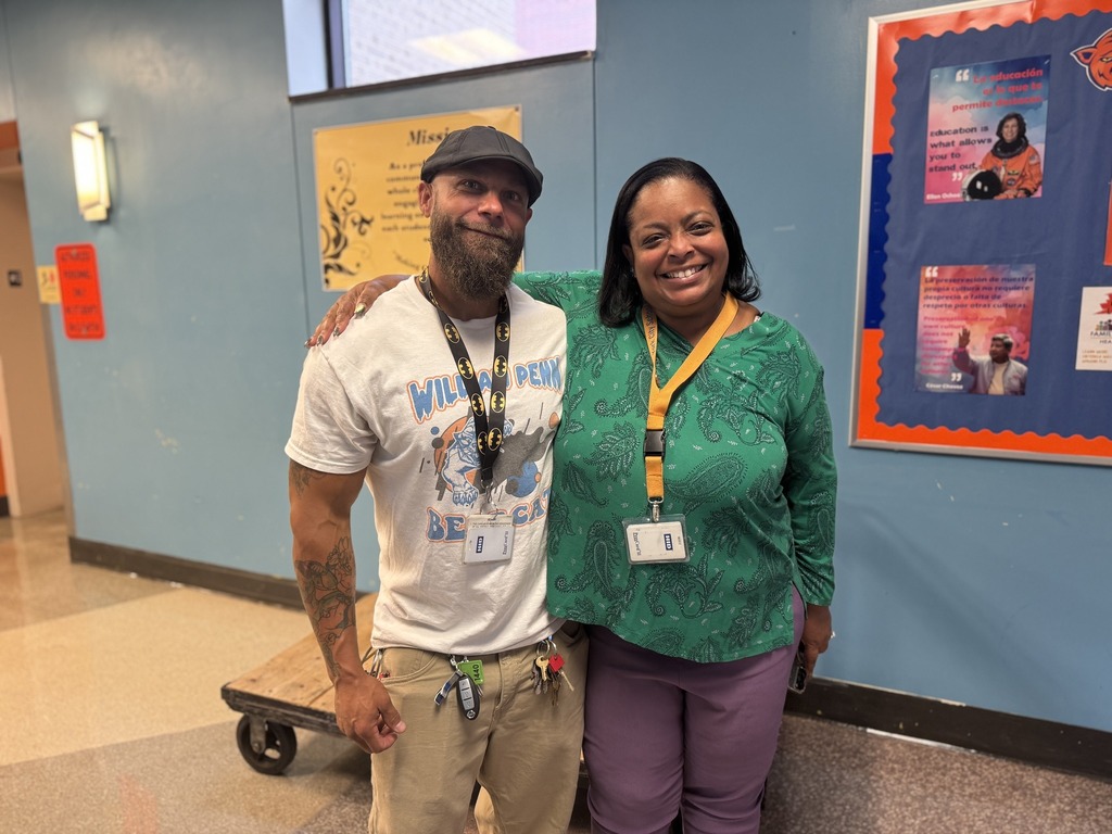 Superintendent of Schools, Dr. Andrea Berry-Brown and a district staff member are standing in a school hallway, both of them wearing ID lanyards.