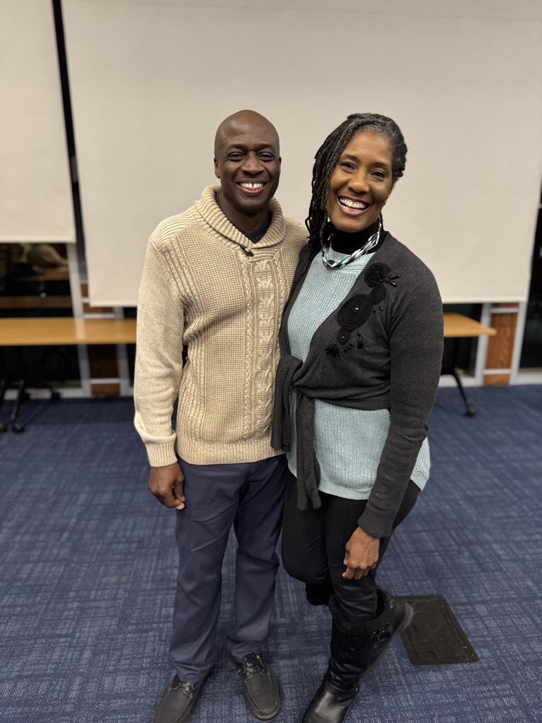The School District of the City of York's newest School Board Director, Halman Smith II and his wife, are standing in a conference room. A table and screens can be seen in the background.