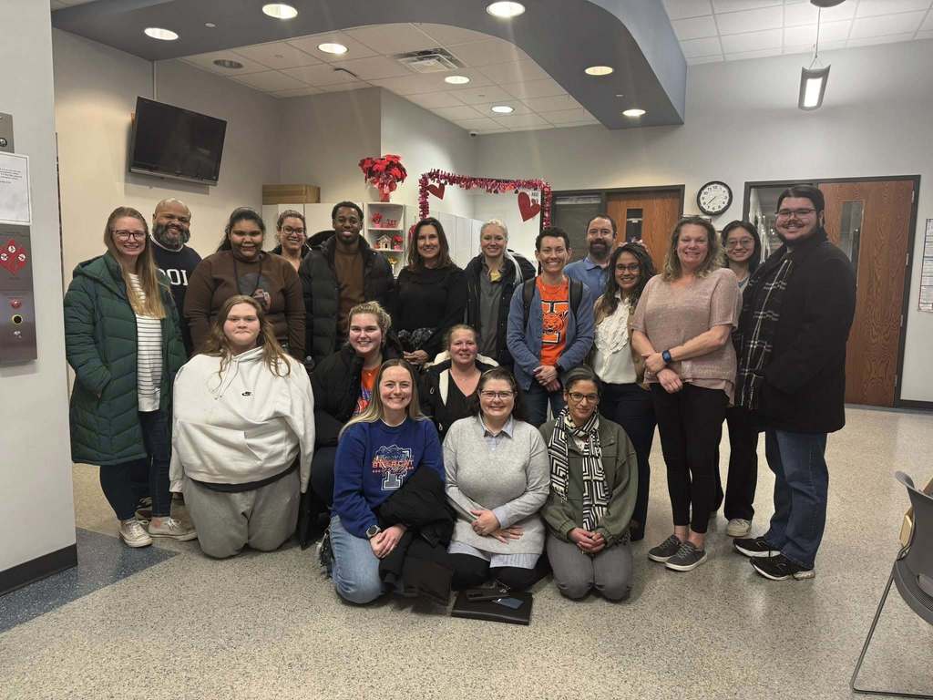 A group of people, including Hannah Penn PreK-8 administrators and staff are standing and sitting down in a lobby area. 