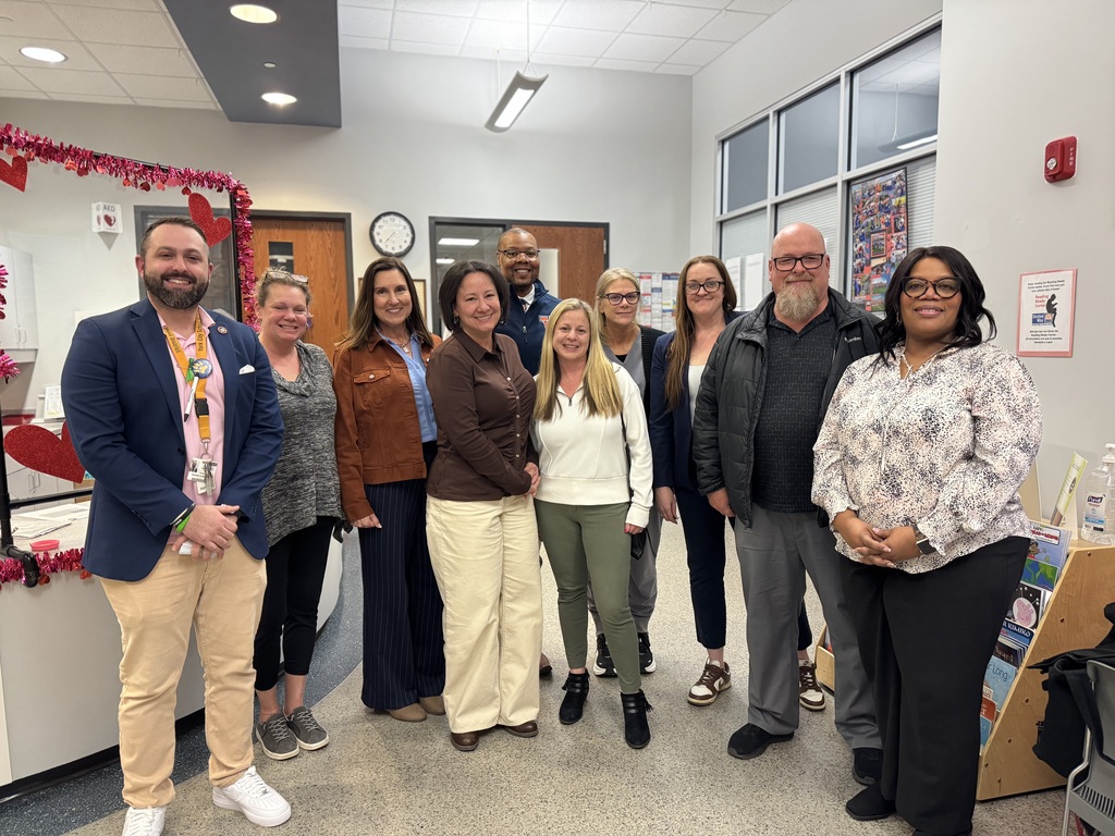 A group of people, including Goode PreK-8 administrators and staff are standing in a lobby area. 