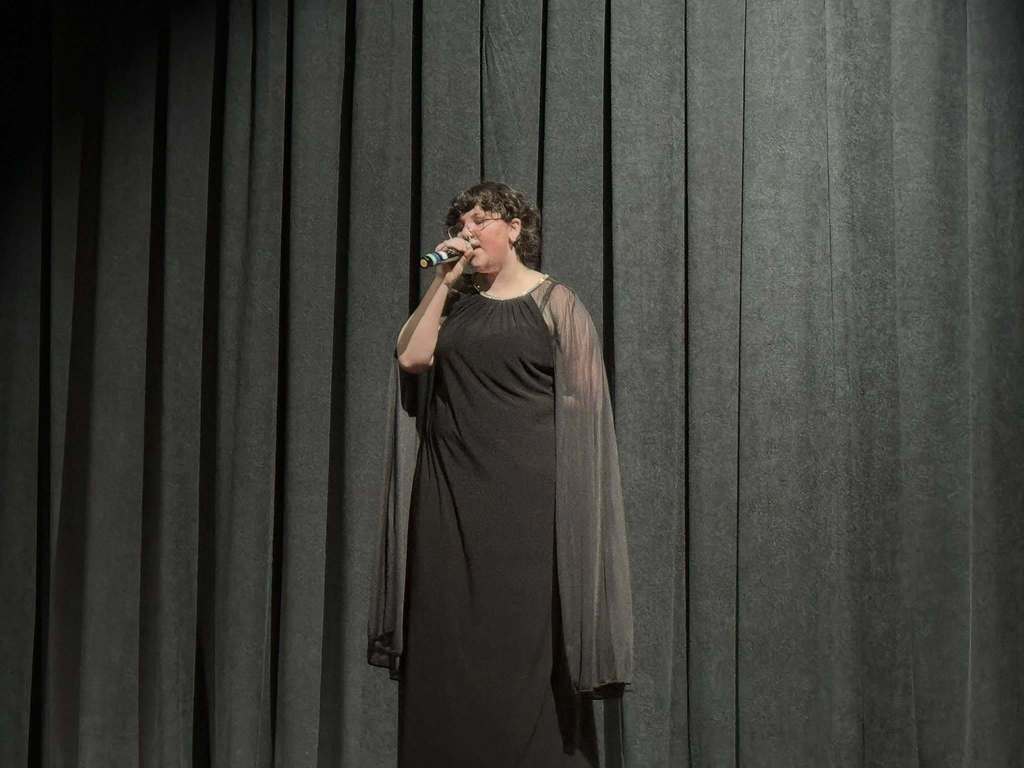 A student is singing into a microphone on stage.