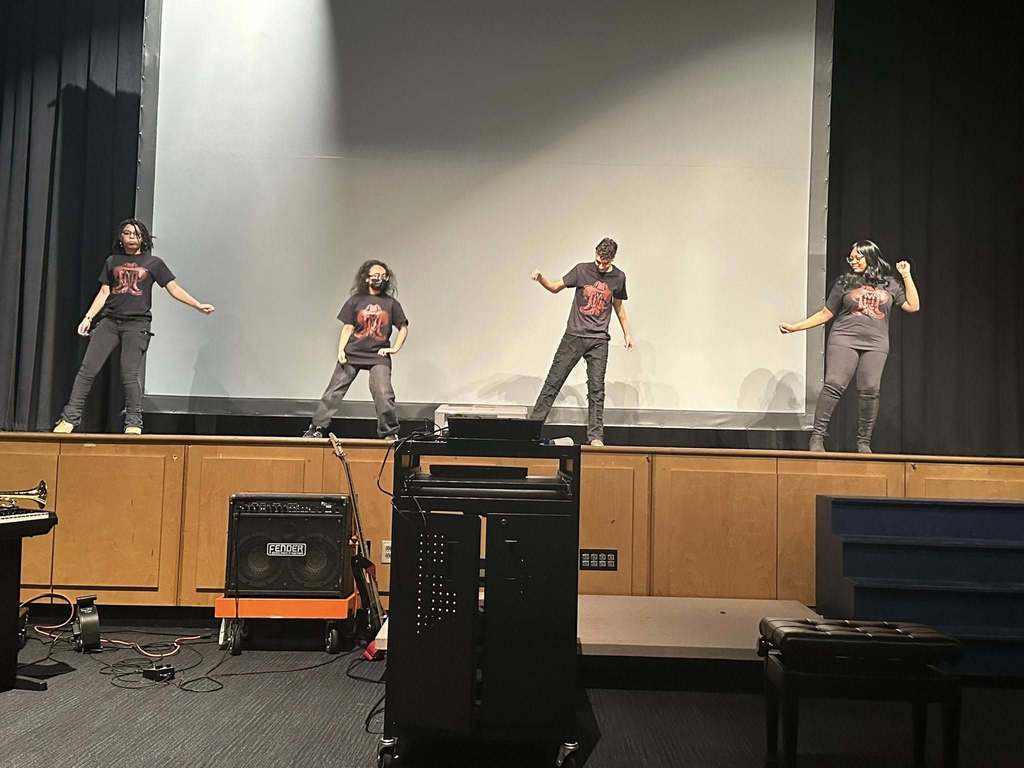 Four students are on performing a choreographed dance on stage.