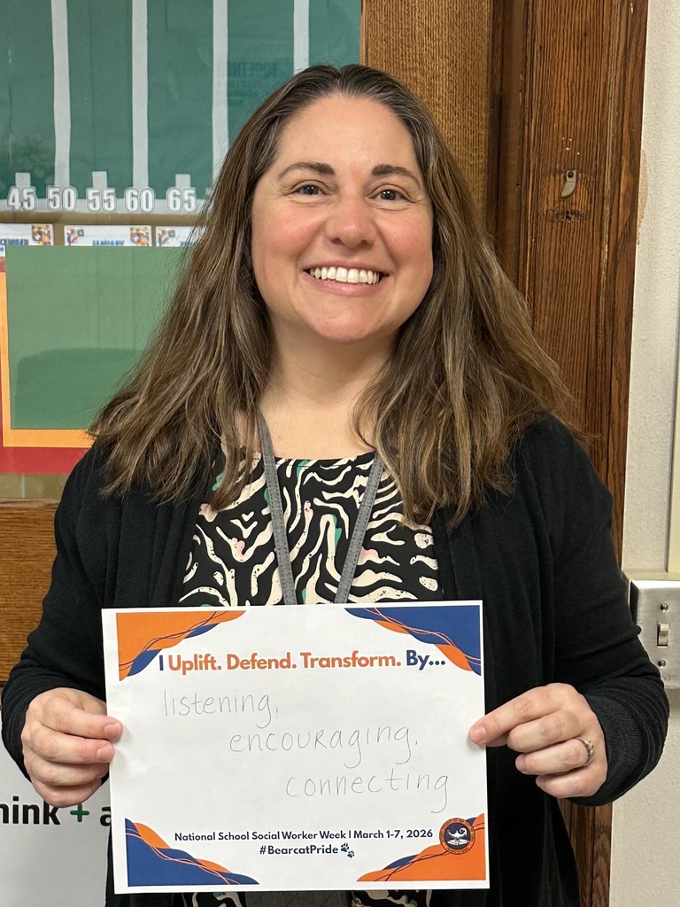 A district staff member is holding a sign that says "I Uplift. Defend. Transform. By... listening, encouraging, connecting."