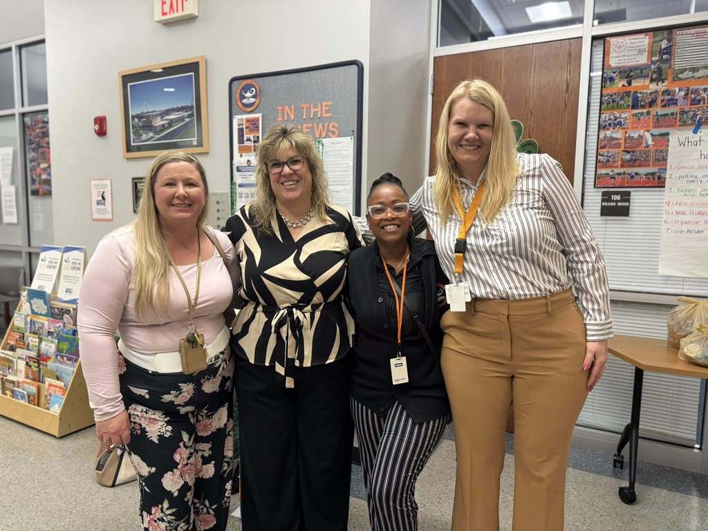 Smith STEAM Academy administrators and two district staff members are standing together in a lobby area.