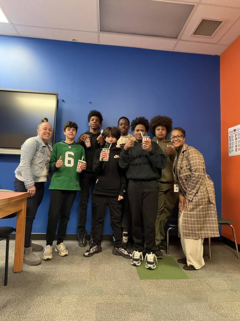 Jackson PreK-8 administrators are standing with a group of students in an open area. The students are holding Rita cups in their hands, with some of them putting their thumbs up.