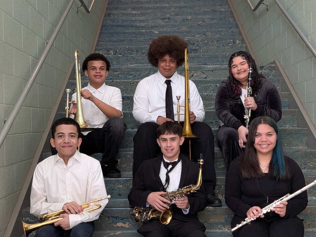 A group of six students are sitting on stairs, each of them holding an instrument. They are smiling and wearing formal attire. 