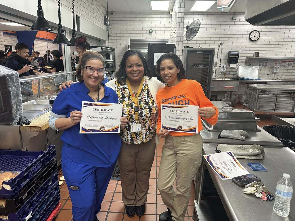 Dr. Andrea Berry-Brown, Superintendent of Schools, is standing in the middle of two district staff members who are holding Perfect Attendance certificates for the second marking period.