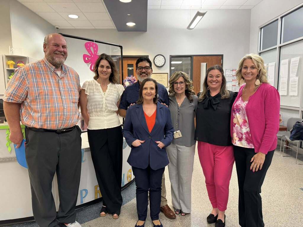 District administrators and staff members are posing together in a lobby area. 