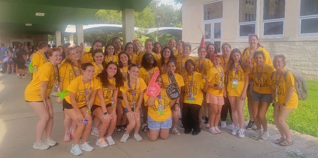 A large group of Best Buddies participants and volunteers are posing together outdoors in matching yellow shirts during a Best Buddies Leadership Conference.
