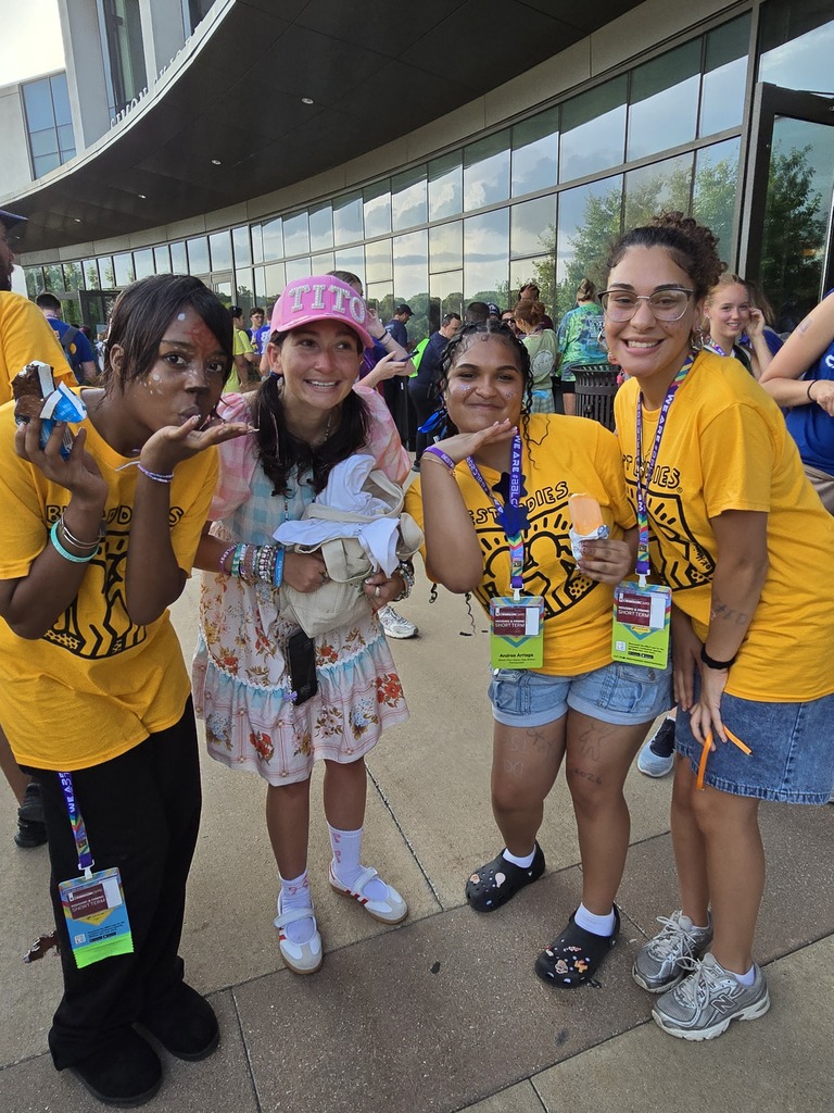Four Best Buddies participants and volunteers are posing together outdoors while enjoying frozen treats during a Best Buddies Leadership Conference.