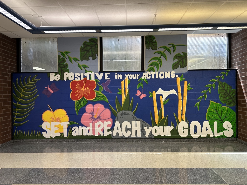 A vibrant tropical-themed mural in a school hallway features flowers, bamboo, butterflies, and lush greenery surrounding the message, "Be Positive in Your Actions. Set and Reach Your Goals."