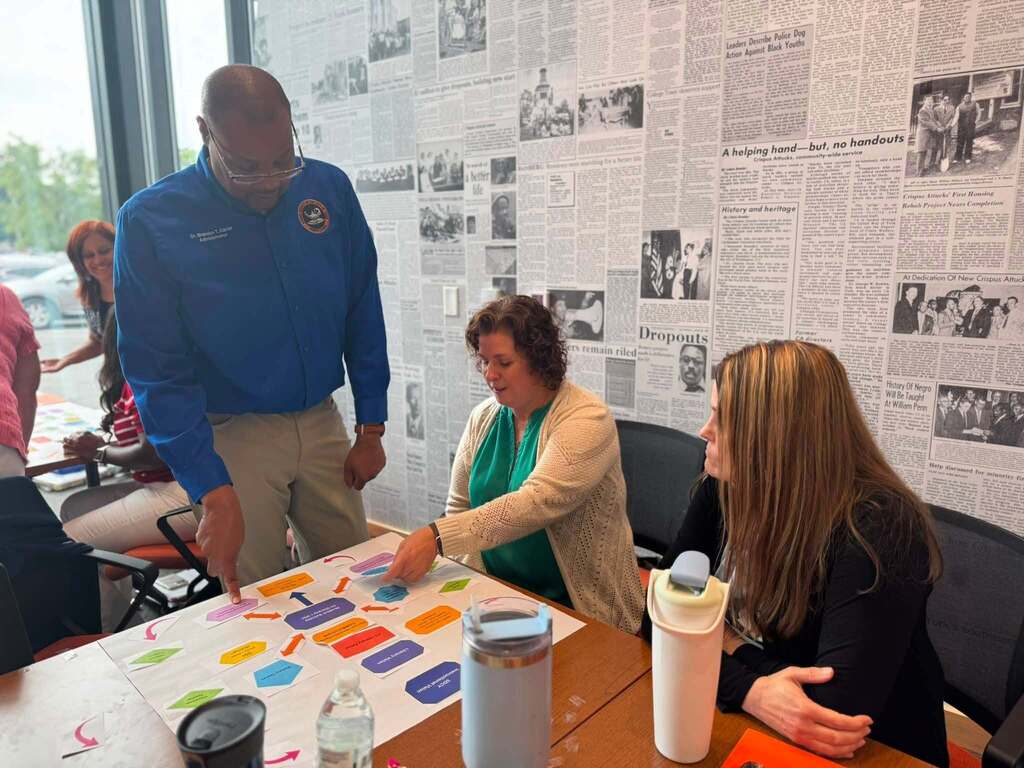 District staff members collaborate around a table, reviewing a colorful planning activity during a professional development session.