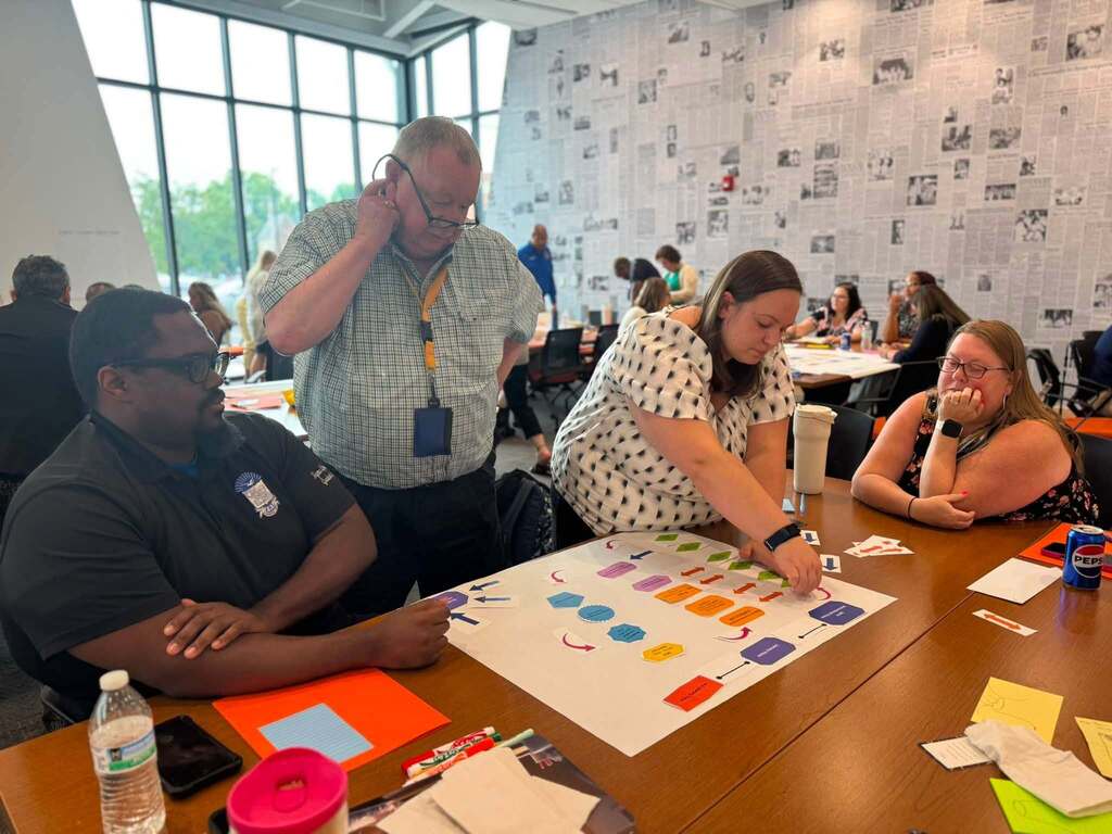 District staff members collaborate around a table, arranging a colorful planning activity during a professional development workshop.