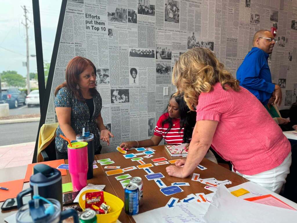 District staff members collaborate around a table, discussing a colorful planning activity during a professional development workshop.