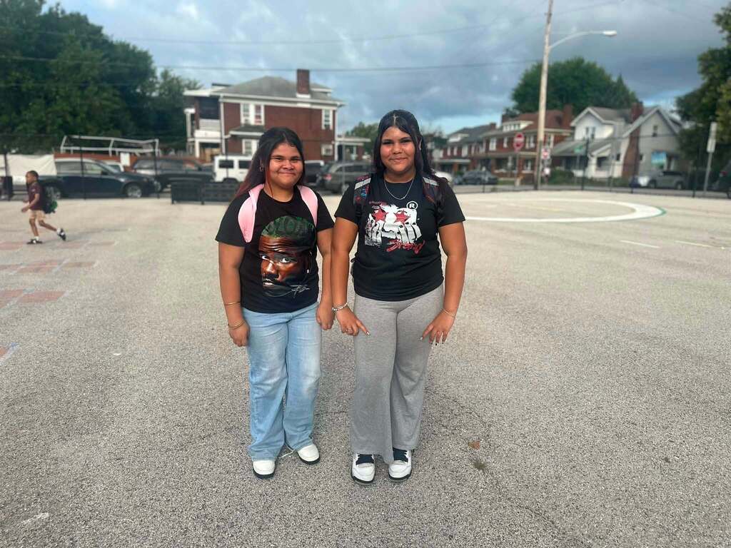 Two students are posing together outdoors on a school playground.