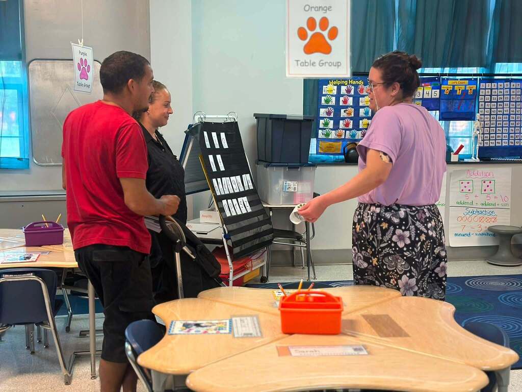 A district staff member is engaging in a conversation with an adult man and woman.