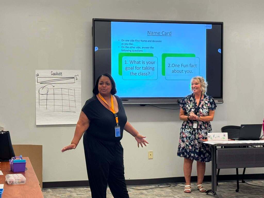 Superintendent of Schools, Dr. Andrea Berry-Brown is presenting to a group of students in a learning lab. A woman can be seen standing near Dr. Berry-Brown.