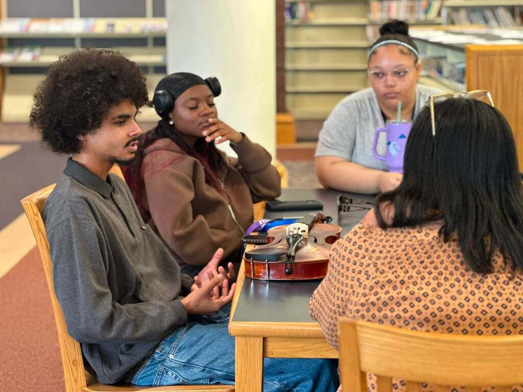 Dr. Andrea Berry-Brown, Superintendent of Schools, engaged in a student-led discussion with a group of William Penn Senior High School students in a school library.