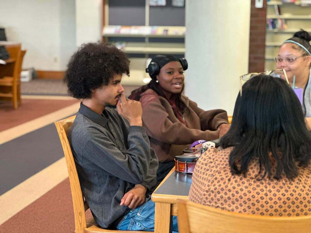 Dr. Andrea Berry-Brown, Superintendent of Schools, engaged in a student-led discussion with a group of William Penn Senior High School students in a school library.