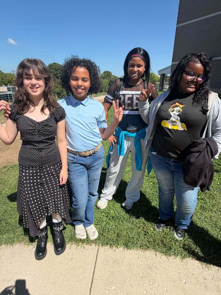 Four students are posing together outdoors. 