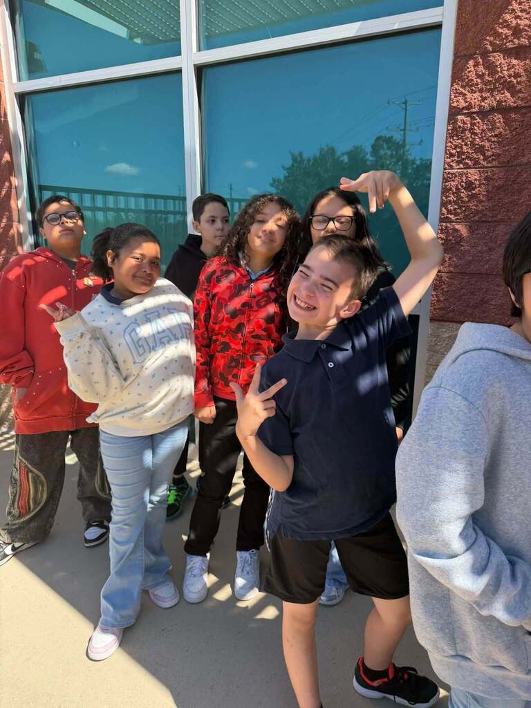 Several students are posing together outside a school building. 