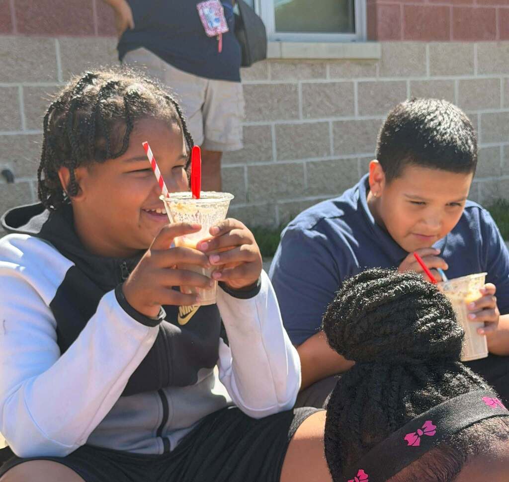 Two students are enjoying frozen treats outdoors. 