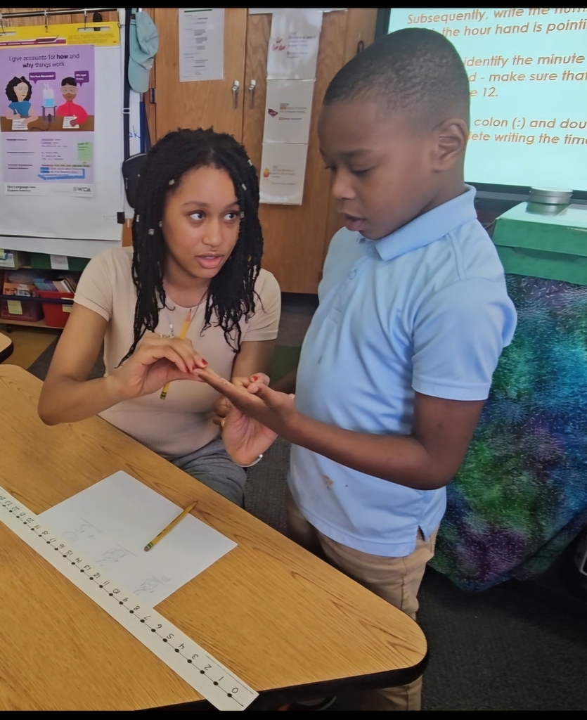 Jackson PreK-8 8th grade students are helping Jackson PreK-8 students in 2nd grade solve addition problems in a school classroom. 