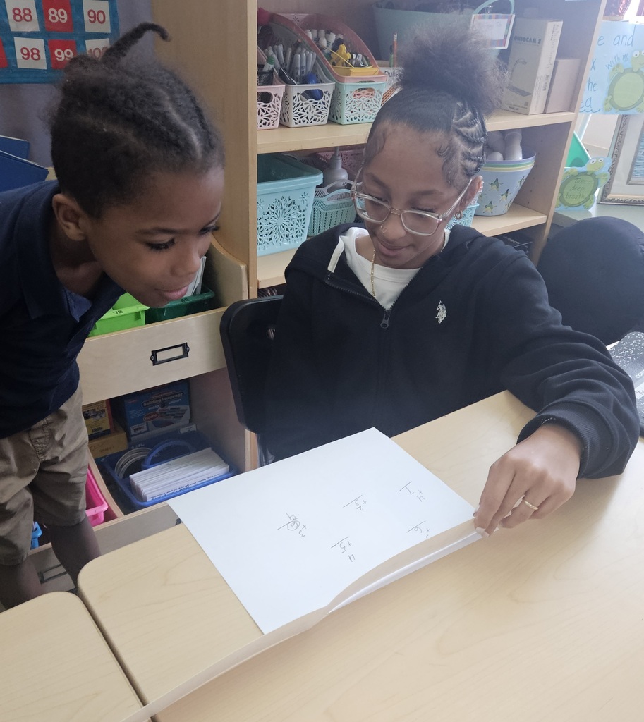 Jackson PreK-8 8th grade students are helping Jackson PreK-8 students in 2nd grade solve addition problems in a school classroom. 