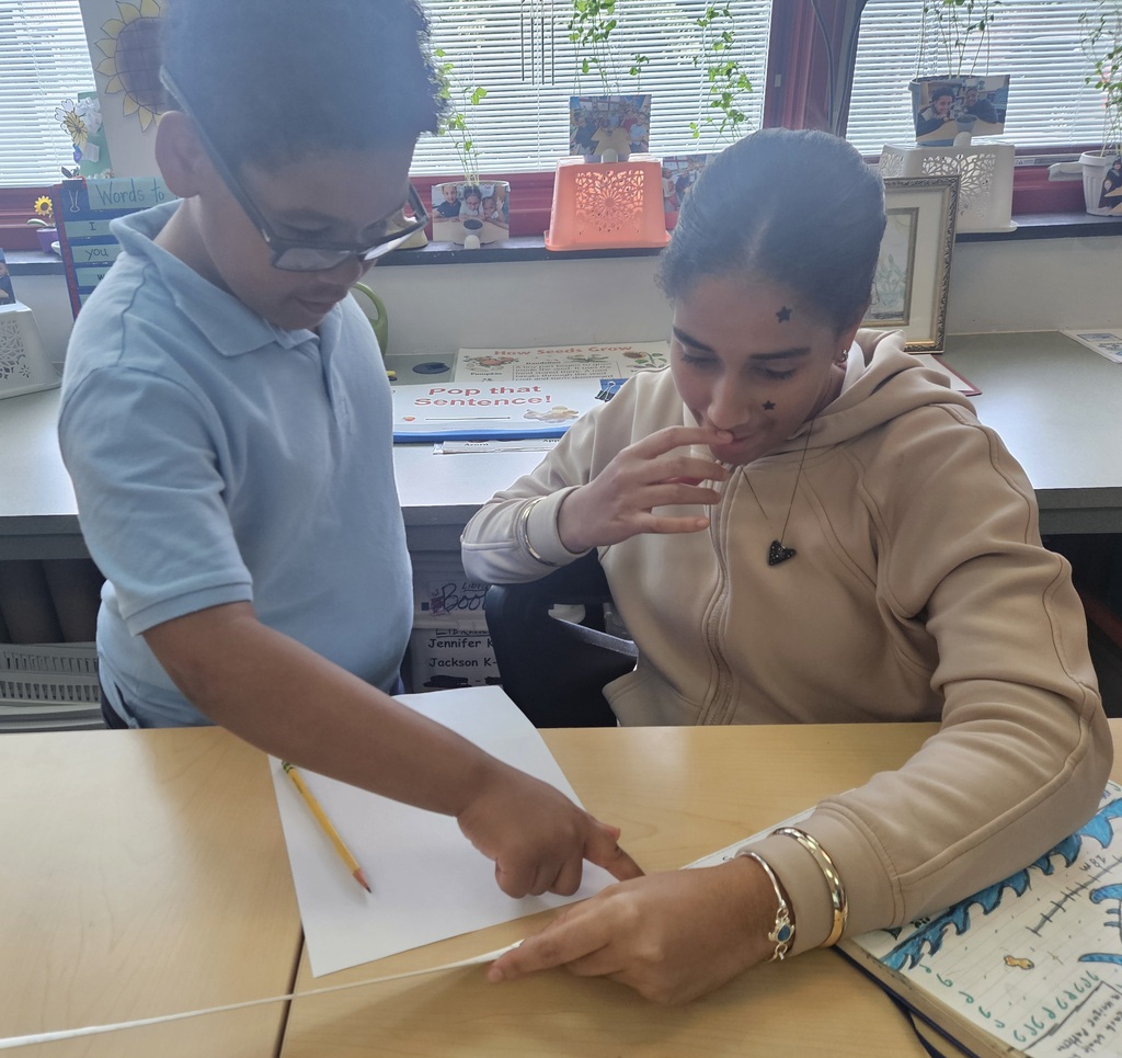Jackson PreK-8 8th grade students are helping Jackson PreK-8 students in 2nd grade solve addition problems in a school classroom. 