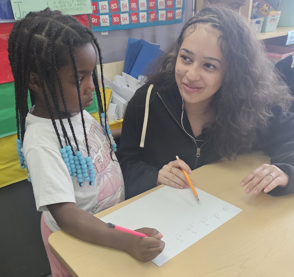 Jackson PreK-8 8th grade students are helping Jackson PreK-8 students in 2nd grade solve addition problems in a school classroom. 