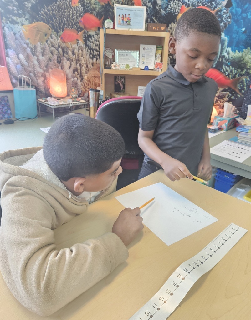 Jackson PreK-8 8th grade students are helping Jackson PreK-8 students in 2nd grade solve addition problems in a school classroom. 