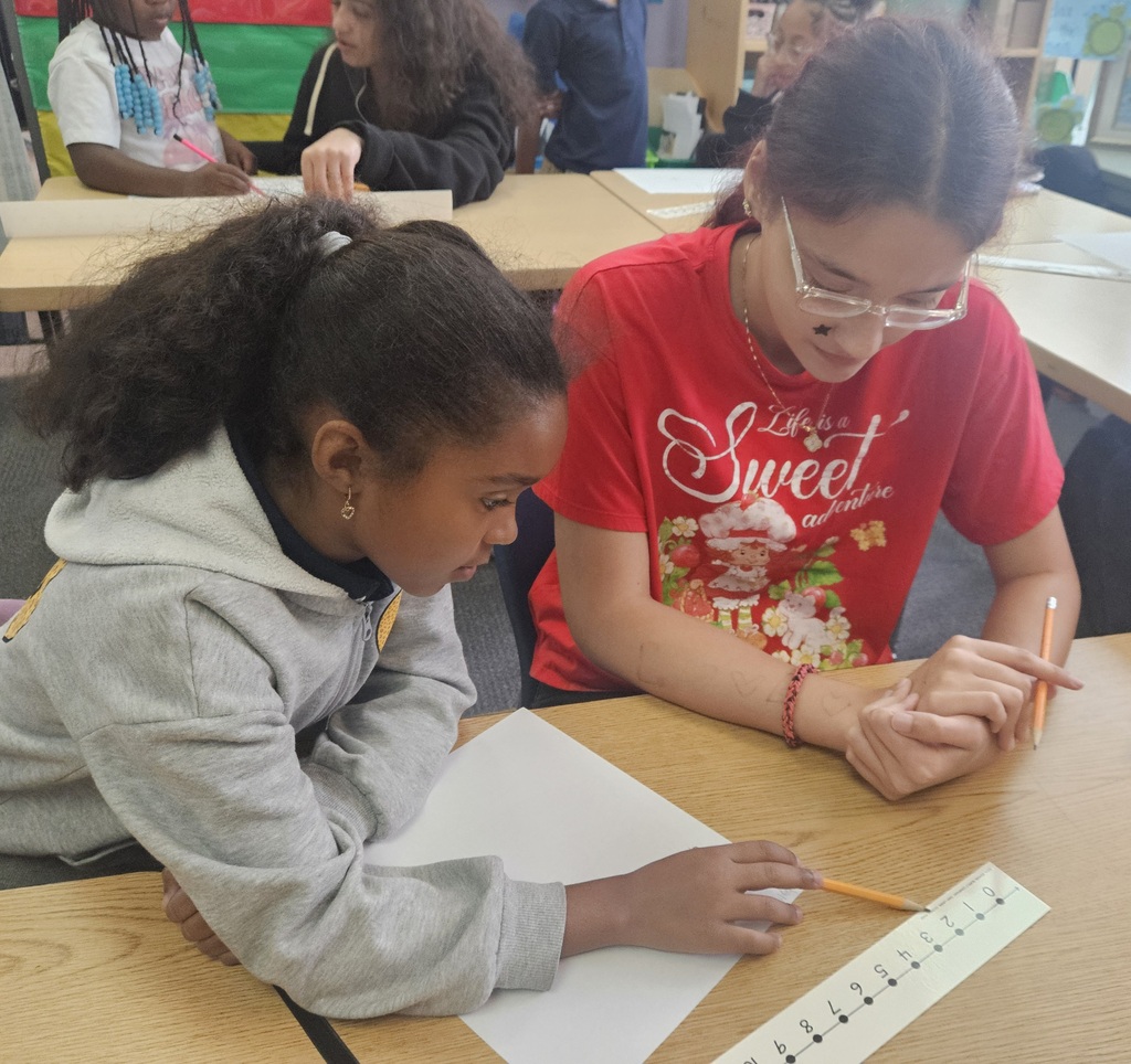 Jackson PreK-8 8th grade students are helping Jackson PreK-8 students in 2nd grade solve addition problems in a school classroom. 