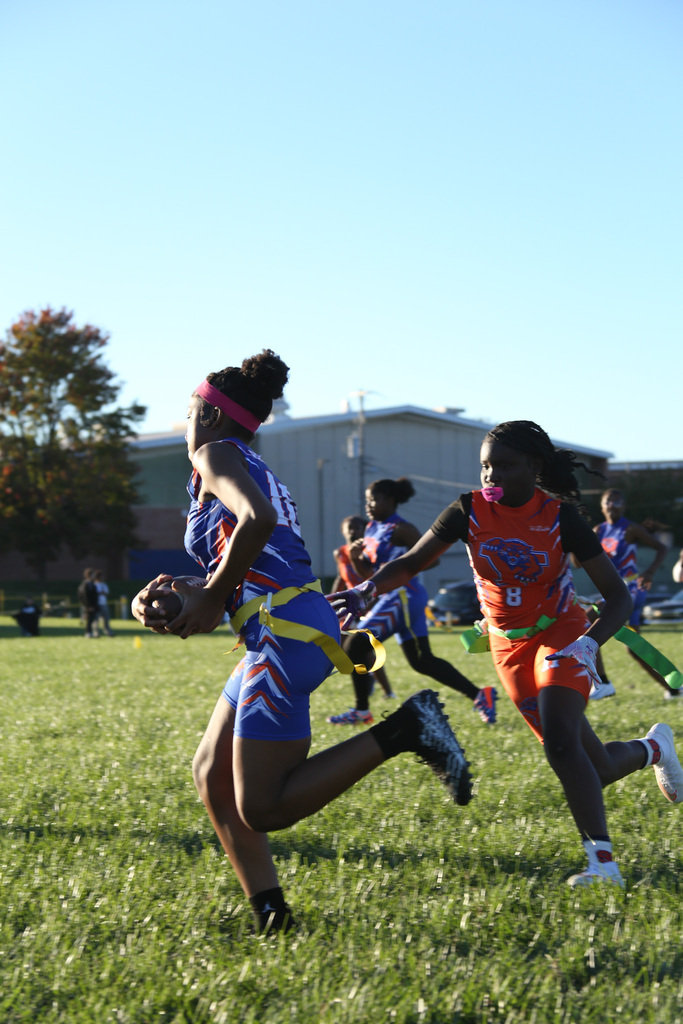 SDCY middle school girls flag football players are competing in a flag football game on a field.