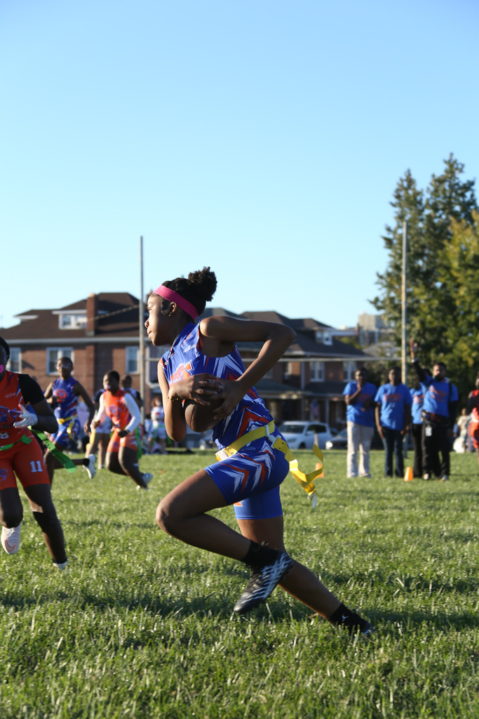 SDCY middle school girls flag football players are competing in a flag football game on a field.