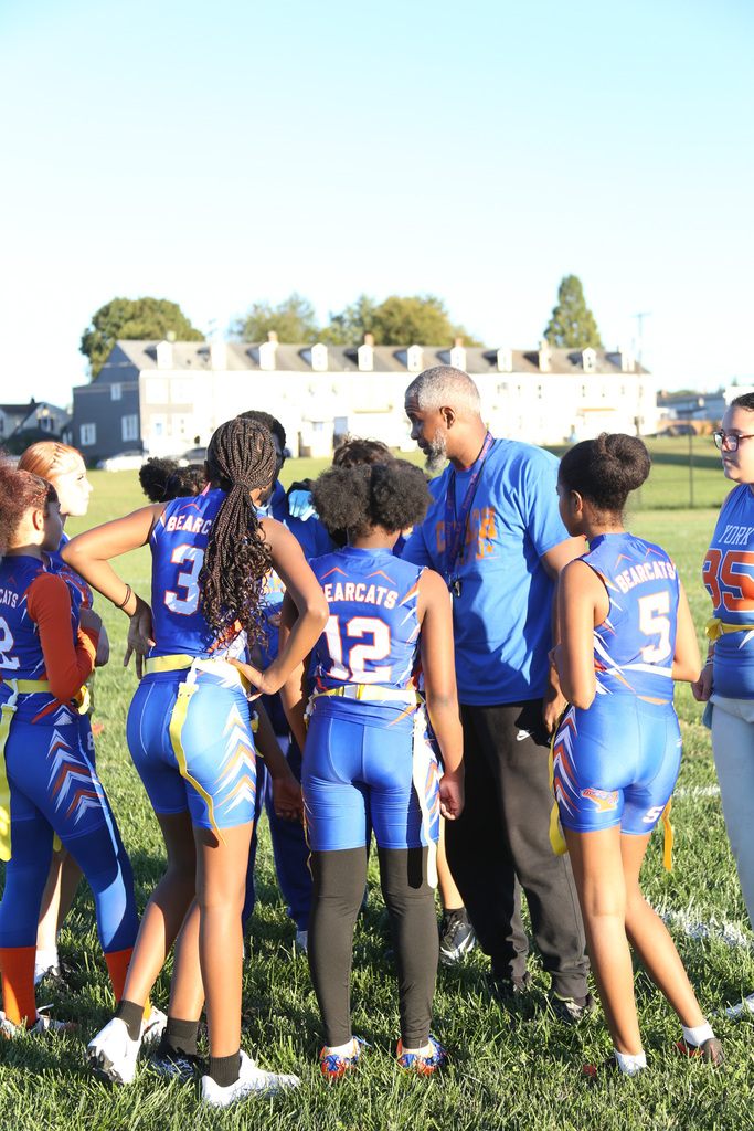SDCY middle school girls flag football players are competing in a flag football game on a field.