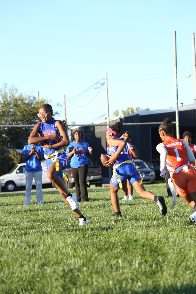 SDCY middle school girls flag football players are competing in a flag football game on a field.