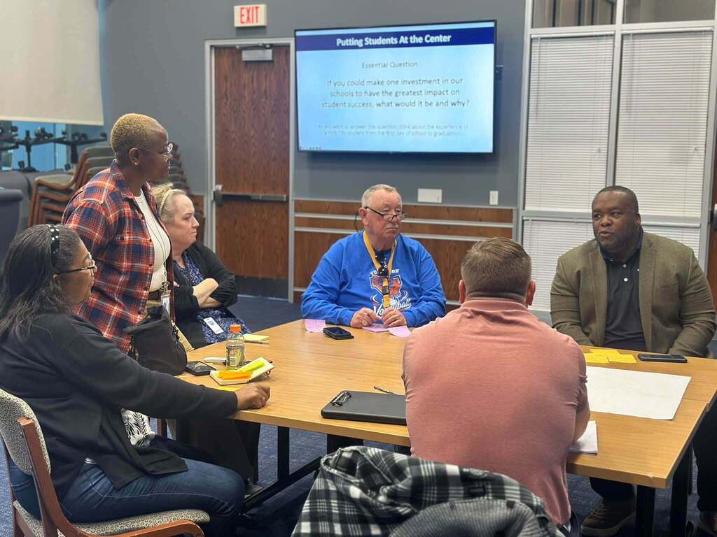 School staff and local community members are participating in a group discussion during a meeting.