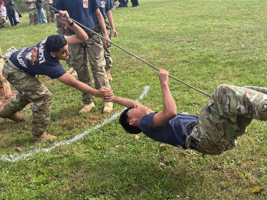 William Penn JROTC cadets working together to complete a rope challenge during a team-building exercise.