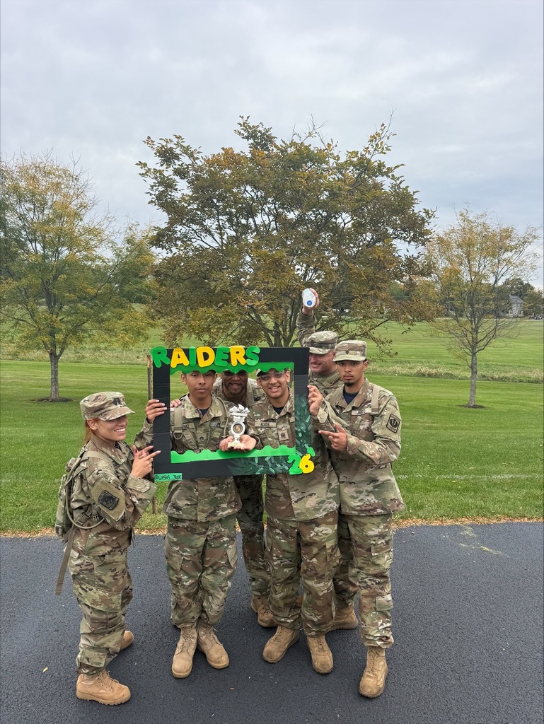 William Penn JROTC cadets are posing together outdoors with a trophy and a decorated “Raiders 26” photo frame.
