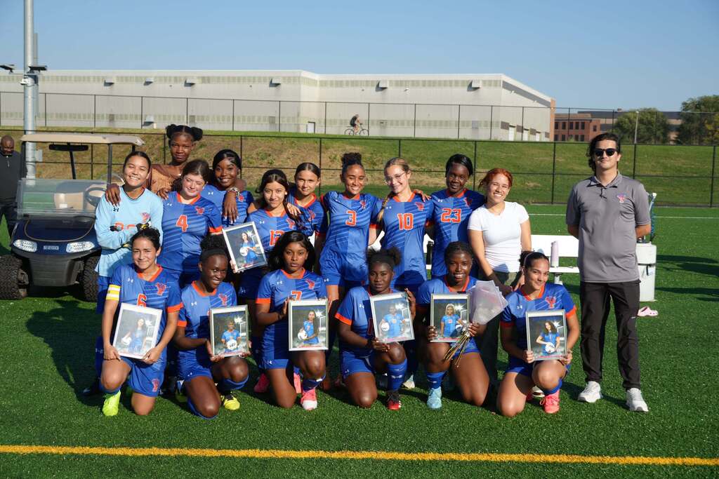 William Penn girls’ soccer team is posing with their coach and framed player photos during Senior Night.